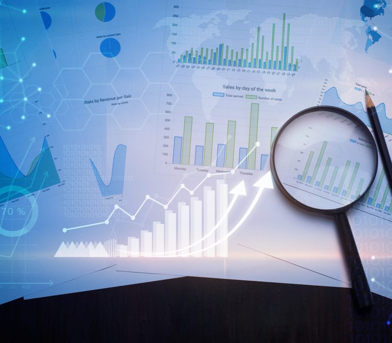 Magnifying glass and documents with analytics data lying on table , and digital virtual reality graph